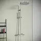 Duschsystem von Ideal Standard mit einem runden, großen Kopfbrause und einem separaten Handbrauseanschluss an einer hellen Wand. Hygienisch und funktional gestaltet.